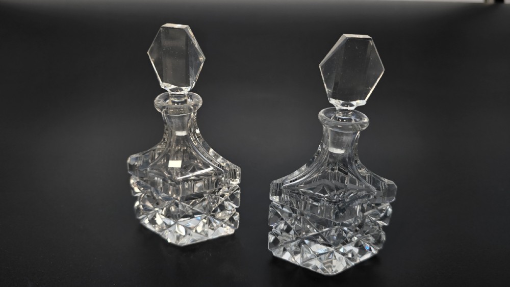 An Art Deco cut lead crystal five-piece cruet set featuring two stoppered bottles and two lidded pots arranged on an integral geometric glass tray. View VIII