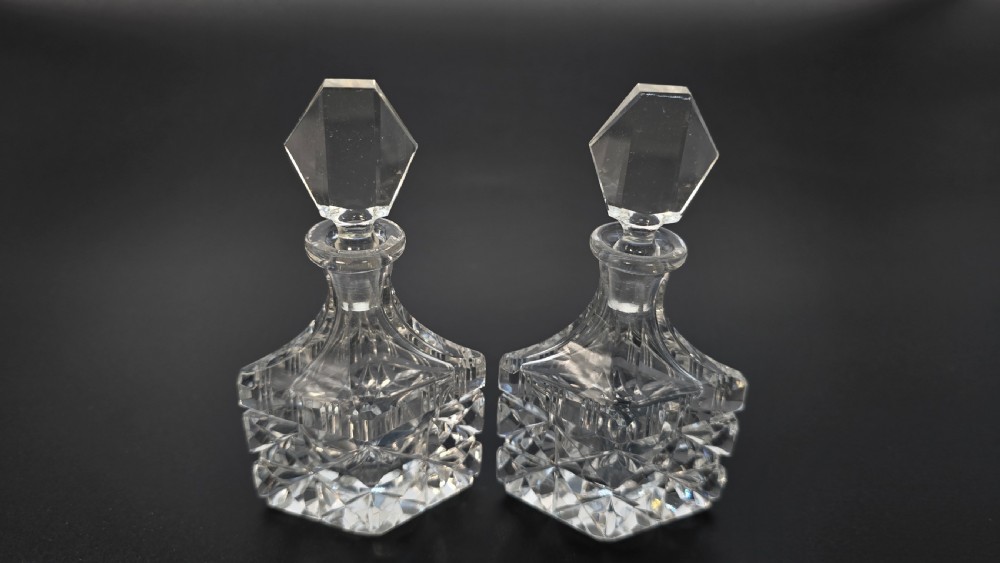 An Art Deco cut lead crystal five-piece cruet set featuring two stoppered bottles and two lidded pots arranged on an integral geometric glass tray. View X