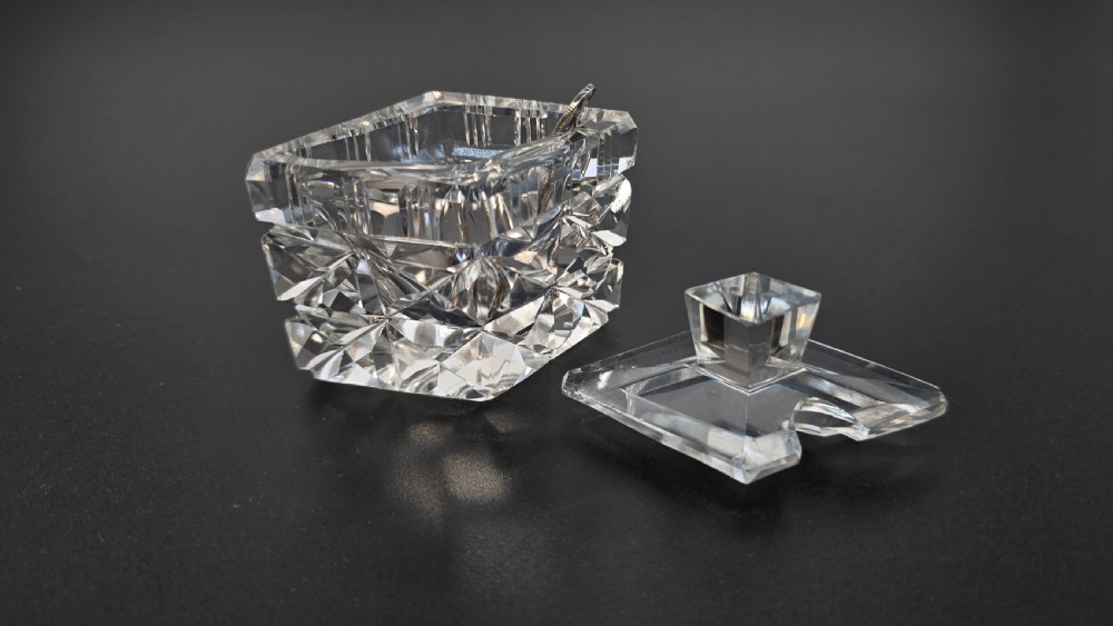 An Art Deco cut lead crystal five-piece cruet set featuring two stoppered bottles and two lidded pots arranged on an integral geometric glass tray. View XII