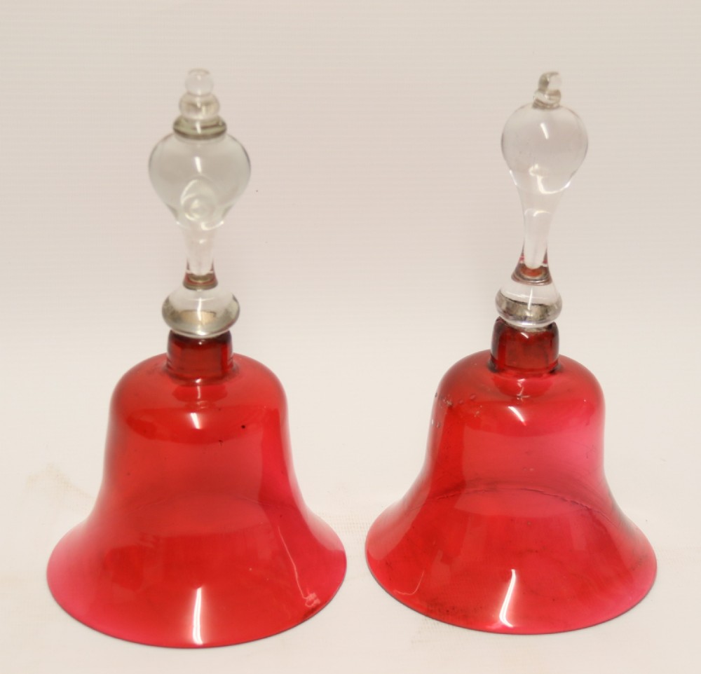 A pair of Victorian hand bells crafted from ruby red glass with clear glass baluster handles. View II