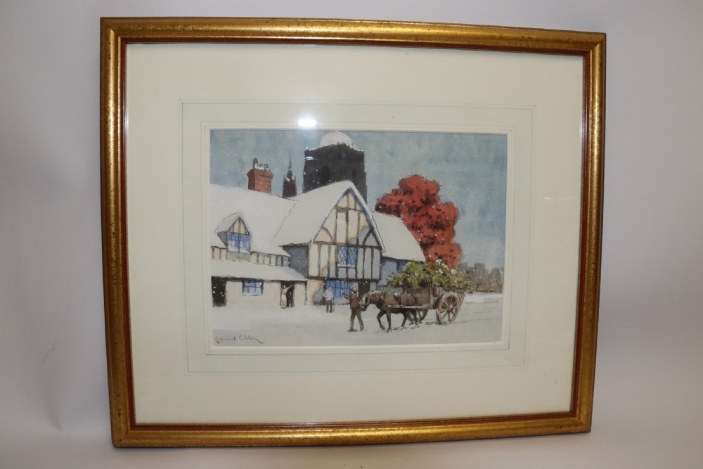 A pair of framed 1930s watercolour paintings by Ernest Uden depicting snowy rural winter scenes featuring a windmill and a timber-framed building. View X