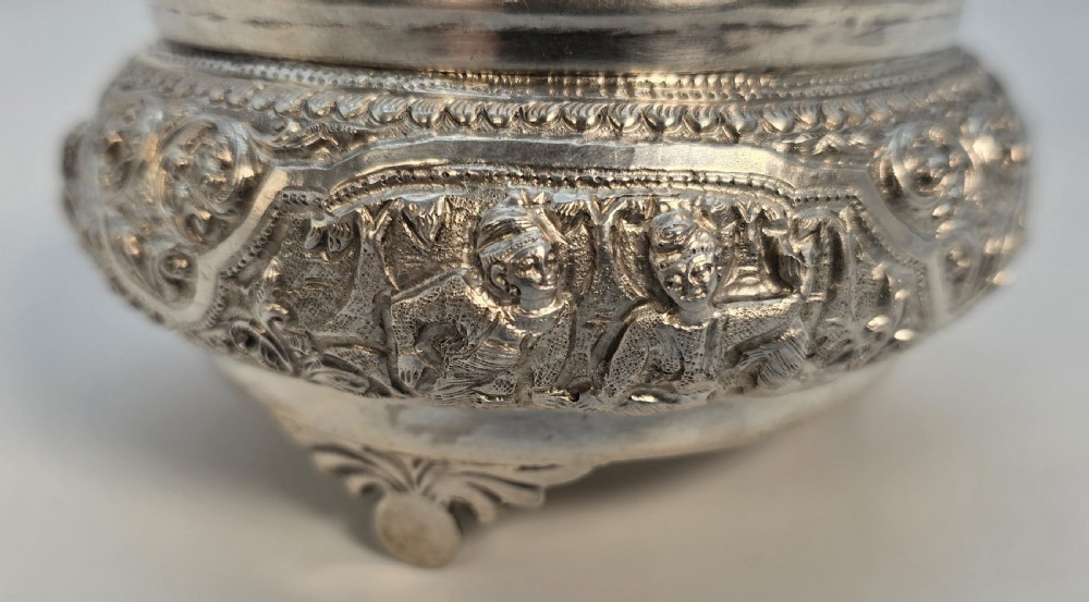 An intricate silver lidded jar featuring raised repousse decorative carving around the body and a small animal finial on top. View XVI