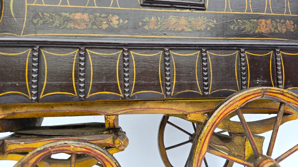 An antique hand-painted wooden model of a Romani gypsy caravan vardo with yellow spoked wheels and floral detail. View XI