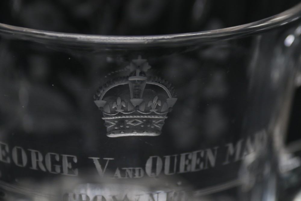 A clear glass commemorative goblet with two loop handles, wheel-engraved with text for the 1911 coronation of King George V and Queen Mary, supported by a faceted stem and starburst base. View X