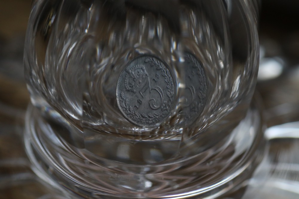 A clear glass commemorative goblet with two loop handles, wheel-engraved with text for the 1911 coronation of King George V and Queen Mary, supported by a faceted stem and starburst base. View XV