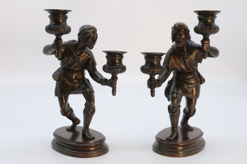 A pair of 19th-century patinated dark bronze double candlesticks featuring sculpted male figures standing on oval bases and holding two sconces each. View II