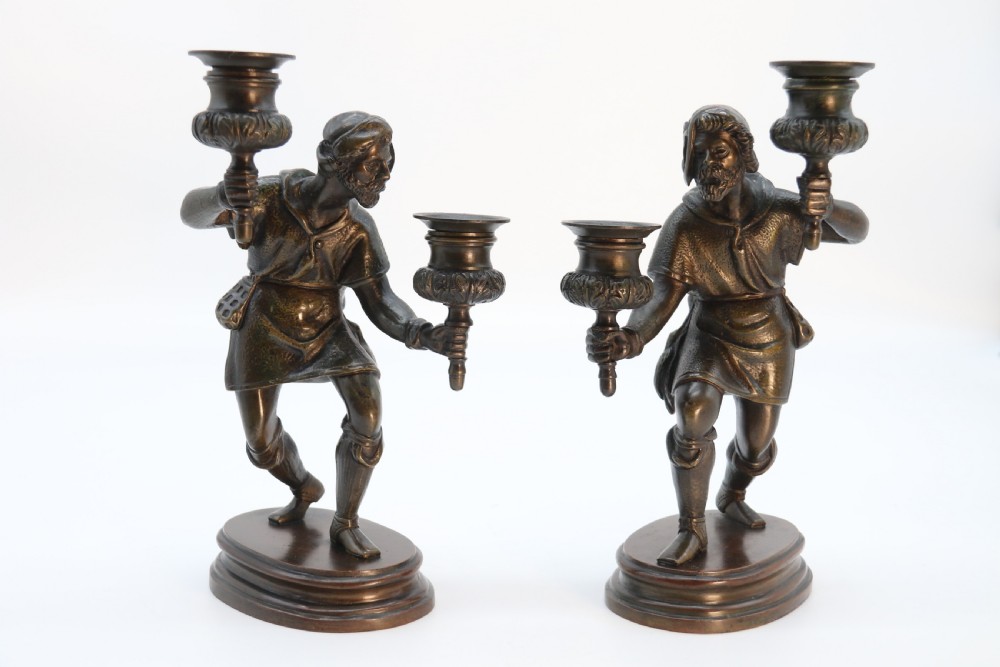 A pair of 19th-century patinated dark bronze double candlesticks featuring sculpted male figures standing on oval bases and holding two sconces each. View III