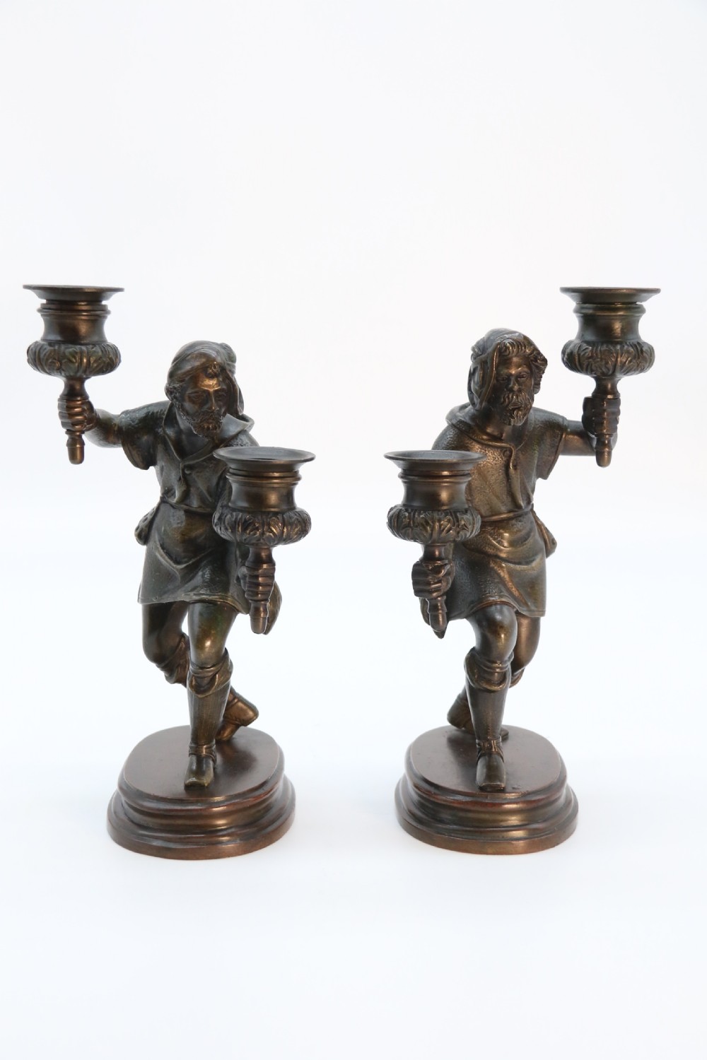 A pair of 19th-century patinated dark bronze double candlesticks featuring sculpted male figures standing on oval bases and holding two sconces each. View IV