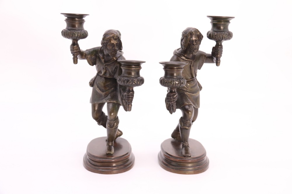 A pair of 19th-century patinated dark bronze double candlesticks featuring sculpted male figures standing on oval bases and holding two sconces each. View IX