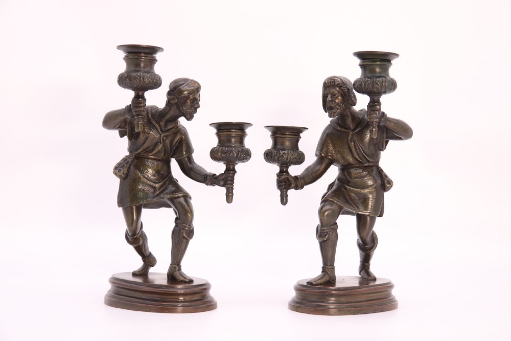 A pair of 19th-century patinated dark bronze double candlesticks featuring sculpted male figures standing on oval bases and holding two sconces each. View XII