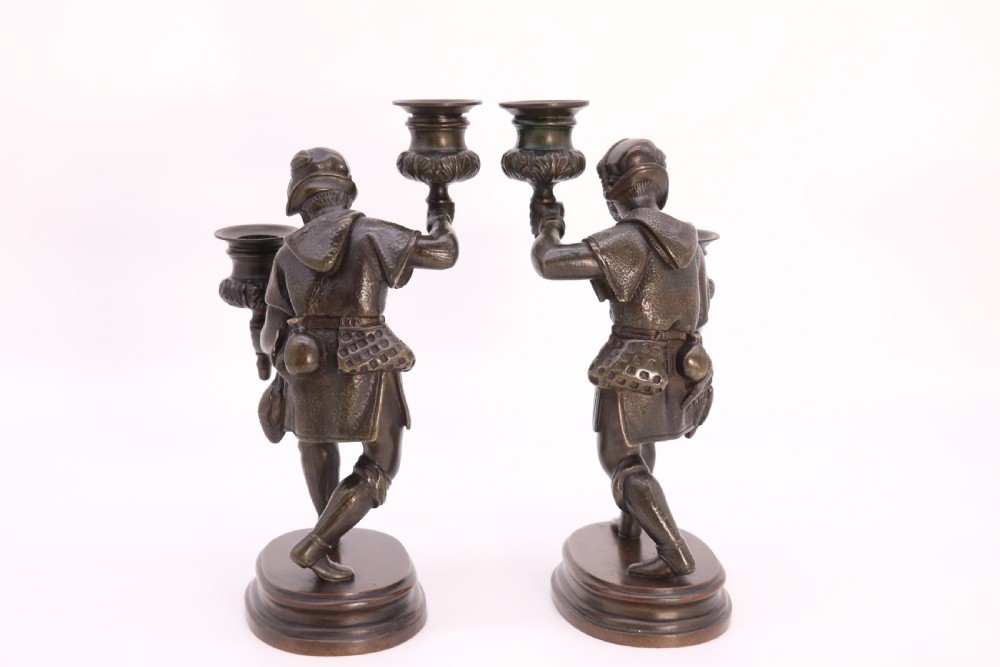 A pair of 19th-century patinated dark bronze double candlesticks featuring sculpted male figures standing on oval bases and holding two sconces each. View XIV