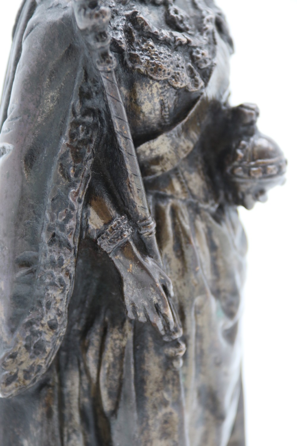 A dark patinated bronze statuette depicting Queen Victoria standing in full ceremonial robes, wearing a crown and holding a sceptre and orb. View VII