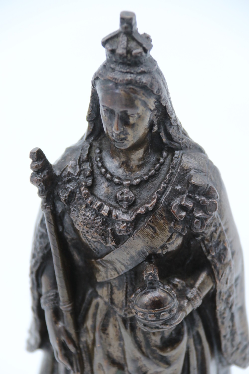 A dark patinated bronze statuette depicting Queen Victoria standing in full ceremonial robes, wearing a crown and holding a sceptre and orb. View VIII