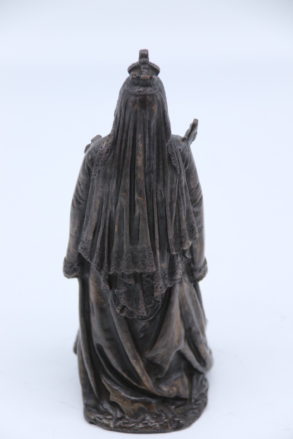A dark patinated bronze statuette depicting Queen Victoria standing in full ceremonial robes, wearing a crown and holding a sceptre and orb. View X