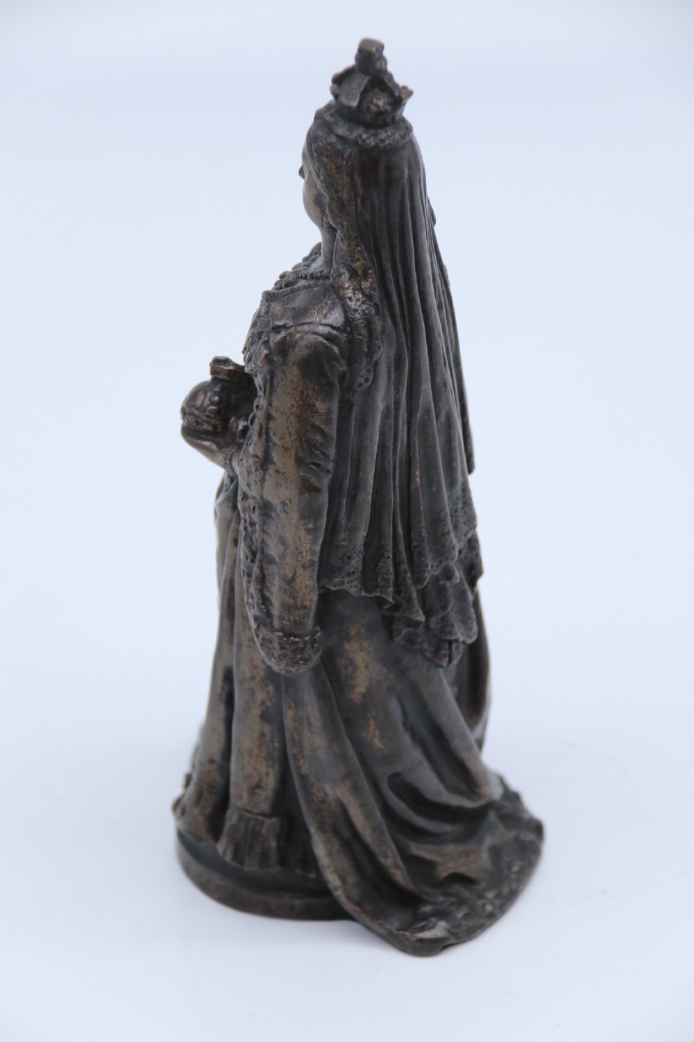 A dark patinated bronze statuette depicting Queen Victoria standing in full ceremonial robes, wearing a crown and holding a sceptre and orb. View XI