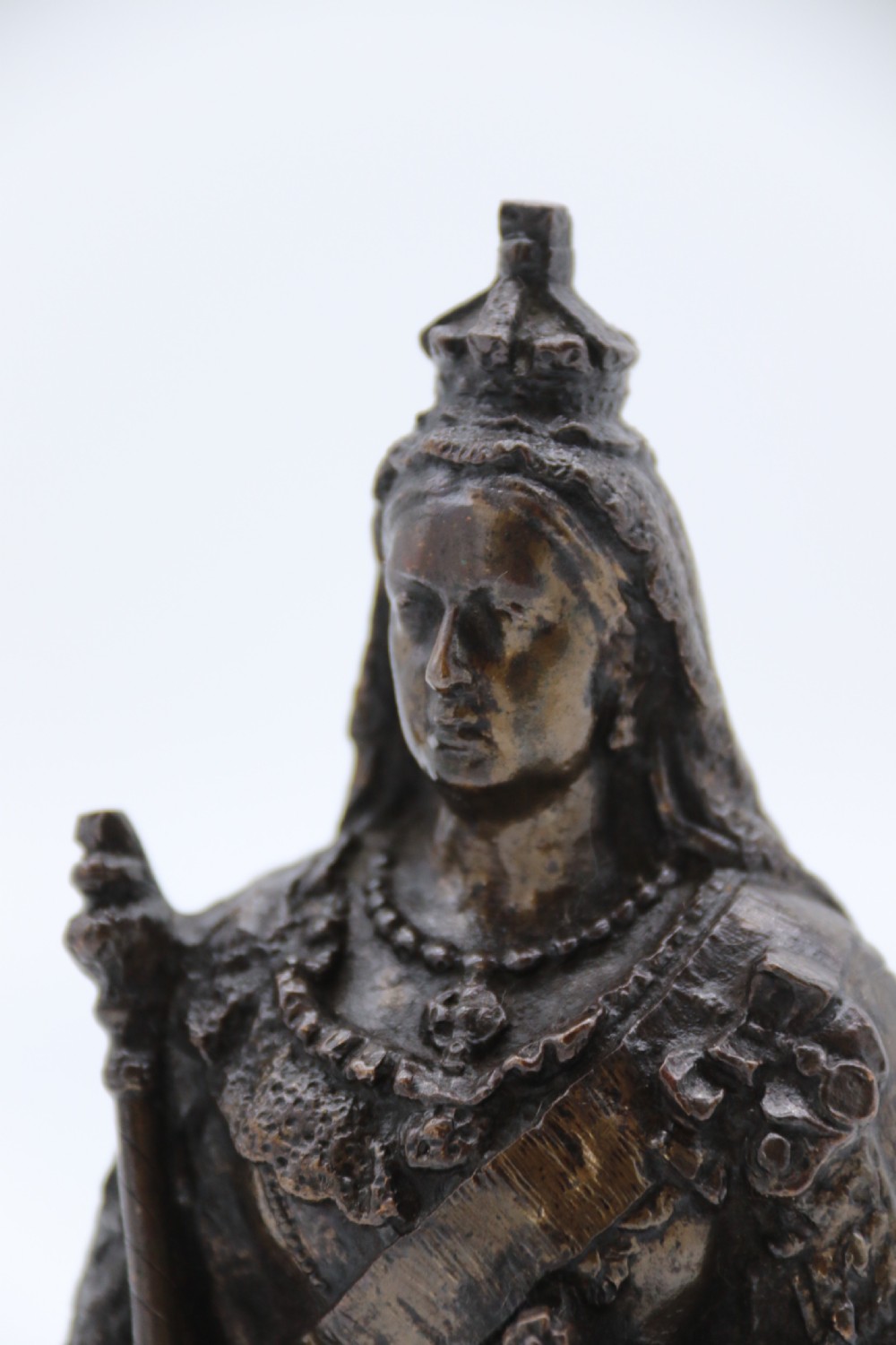 A dark patinated bronze statuette depicting Queen Victoria standing in full ceremonial robes, wearing a crown and holding a sceptre and orb. View XII