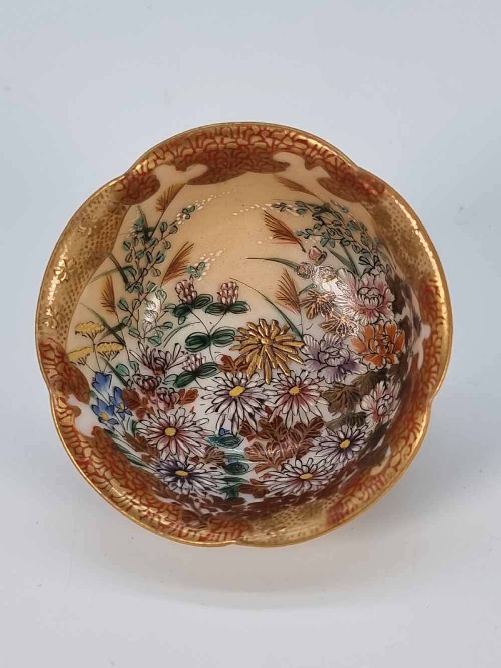 A pair of round Japanese Kutani porcelain miniature bowls with lobed gilded rims and interior hand-painted enamel chrysanthemum motifs. View II