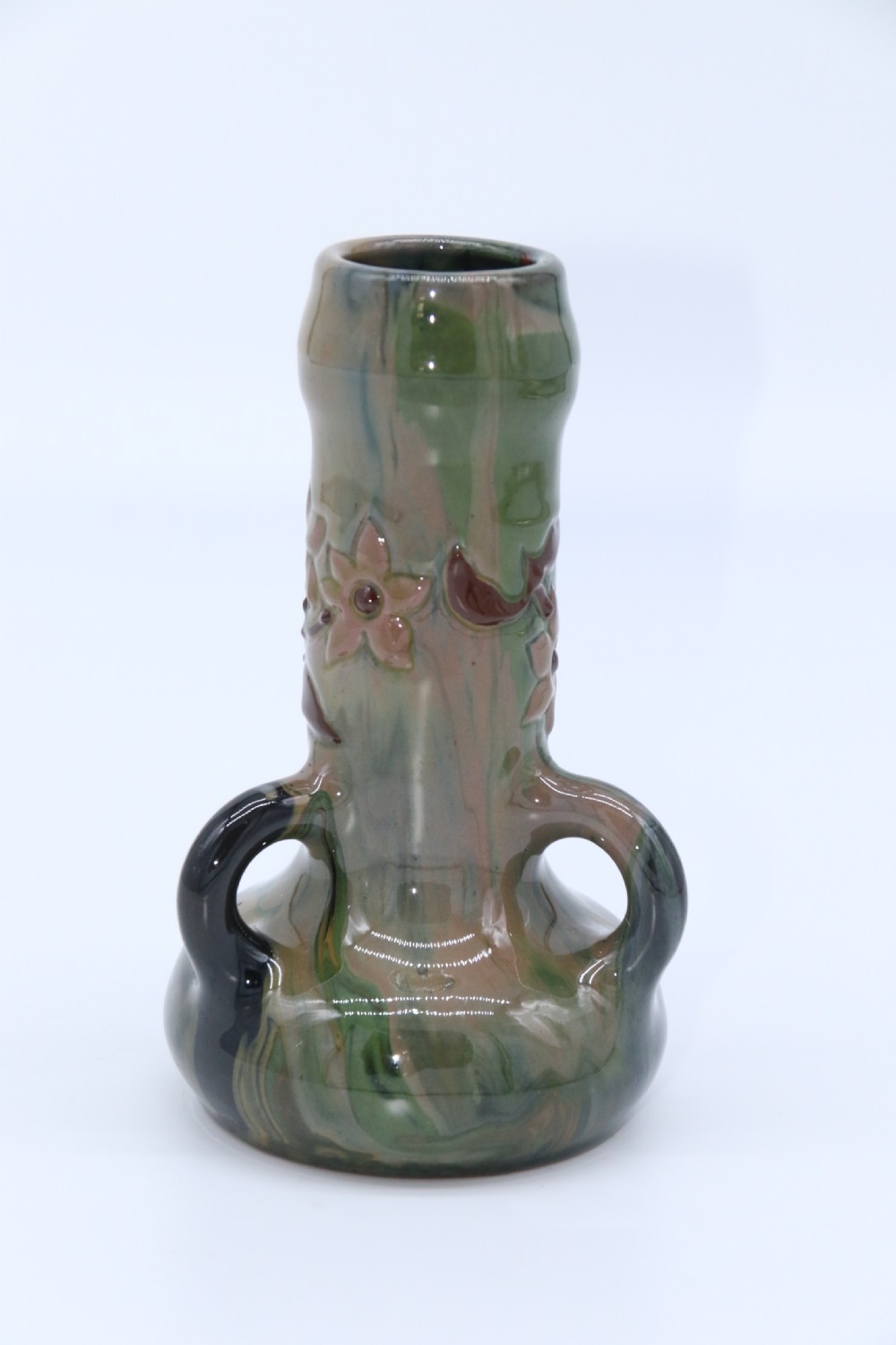 A green and brown glazed earthenware ceramic vase featuring three handles and raised slipware floral decoration. View V