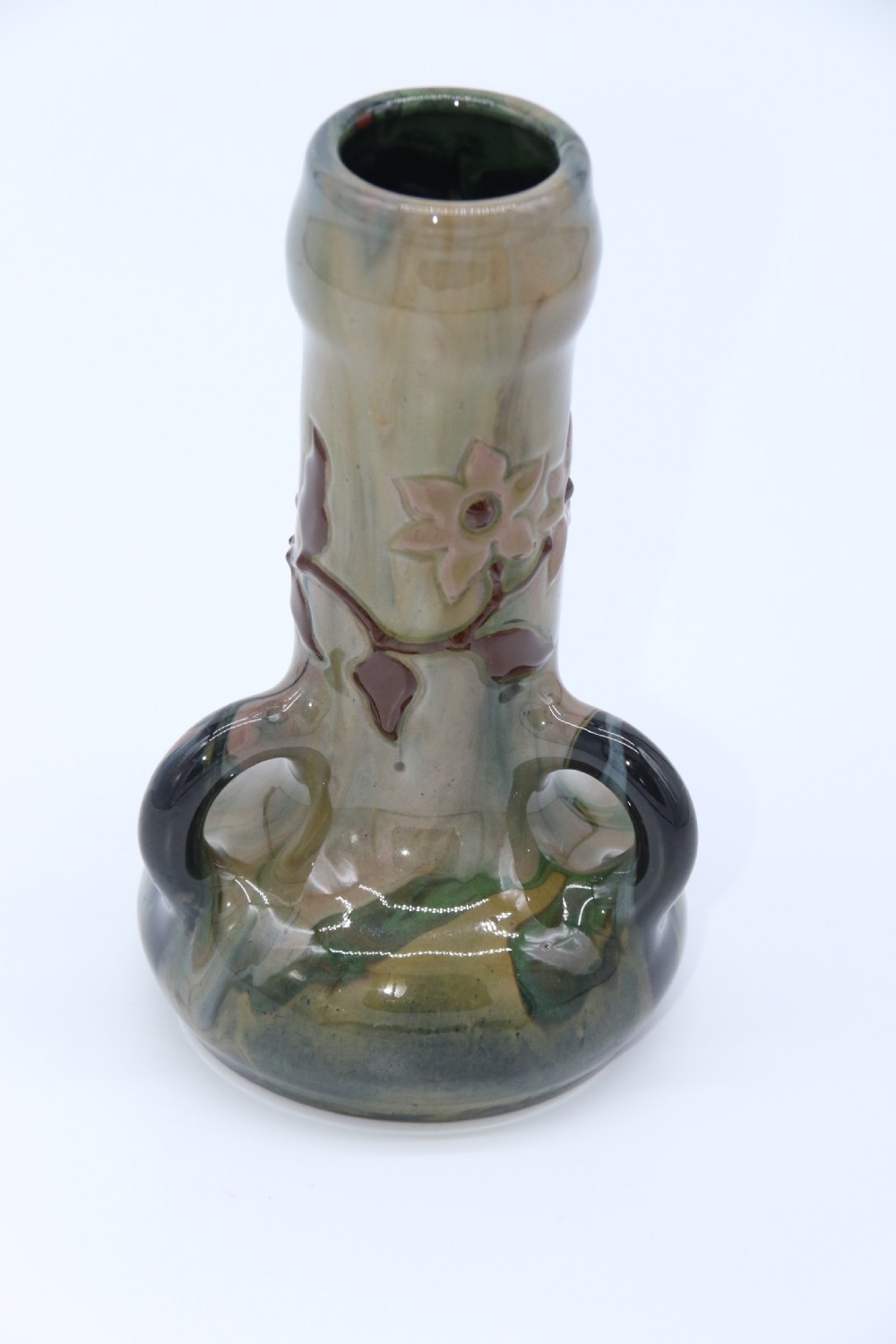 A green and brown glazed earthenware ceramic vase featuring three handles and raised slipware floral decoration. View XI
