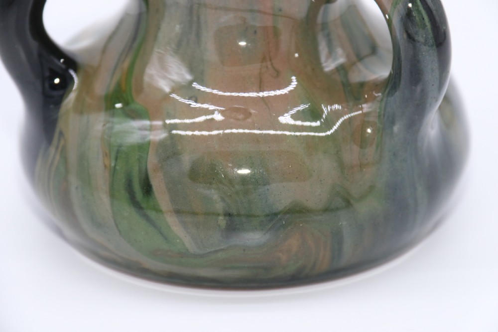 A green and brown glazed earthenware ceramic vase featuring three handles and raised slipware floral decoration. View XII