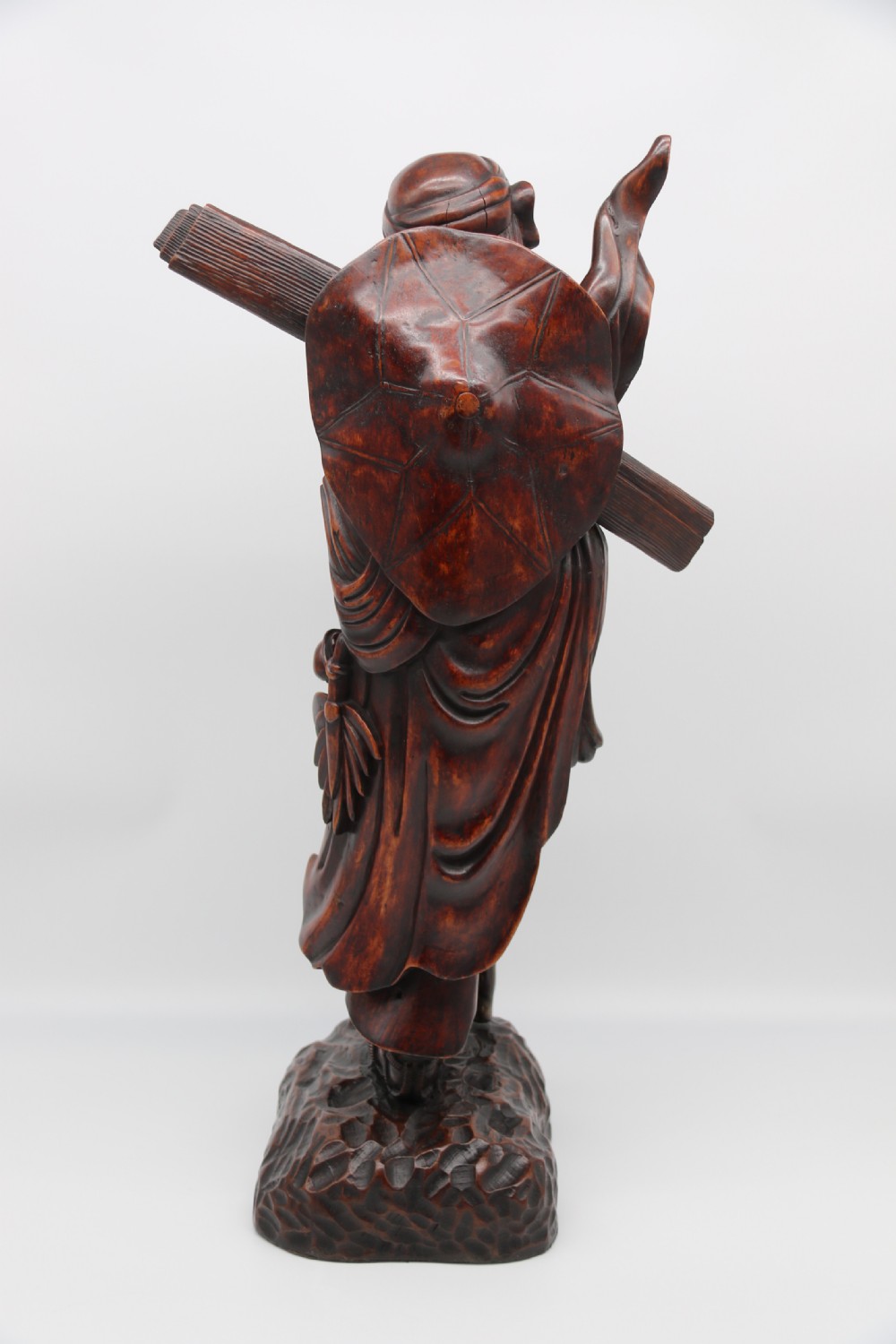 A late 19th-century Japanese Meiji period carved hardwood okimono depicting a standing male figure with a staff, scroll, and fruit on a textured base. View V