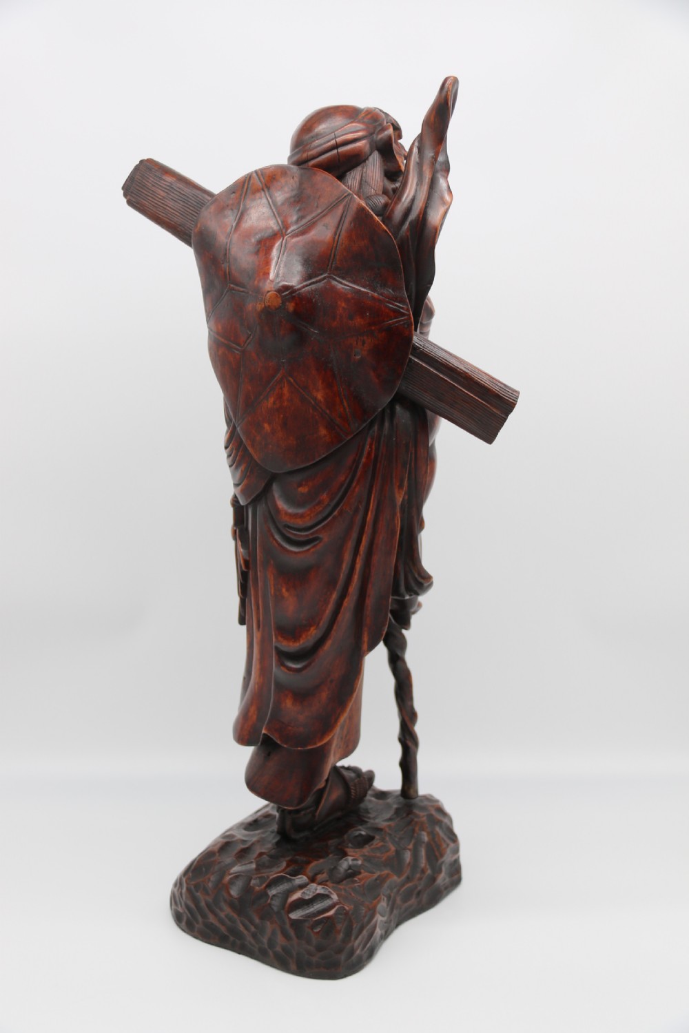 A late 19th-century Japanese Meiji period carved hardwood okimono depicting a standing male figure with a staff, scroll, and fruit on a textured base. View VI