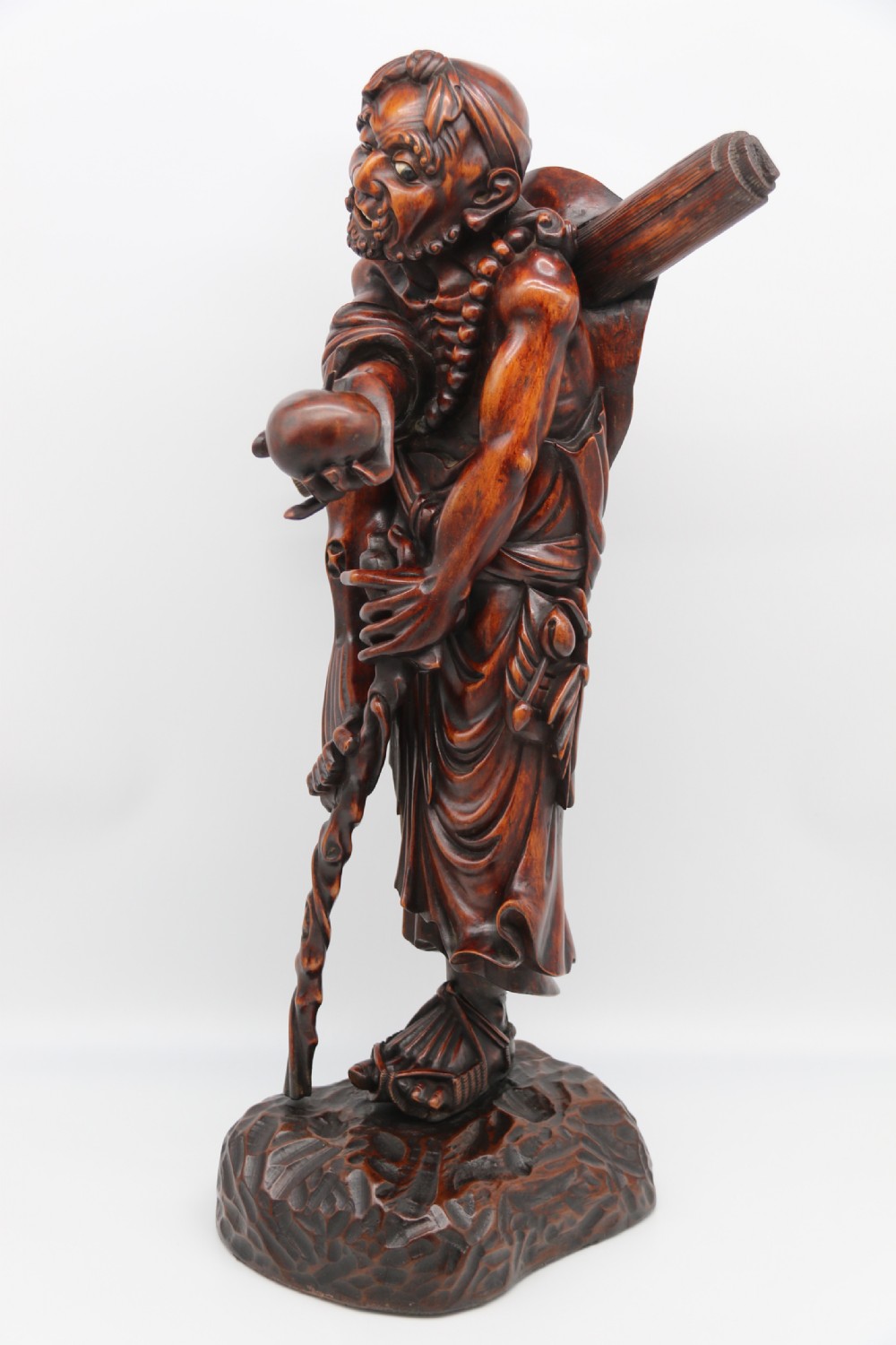 A late 19th-century Japanese Meiji period carved hardwood okimono depicting a standing male figure with a staff, scroll, and fruit on a textured base. View IX