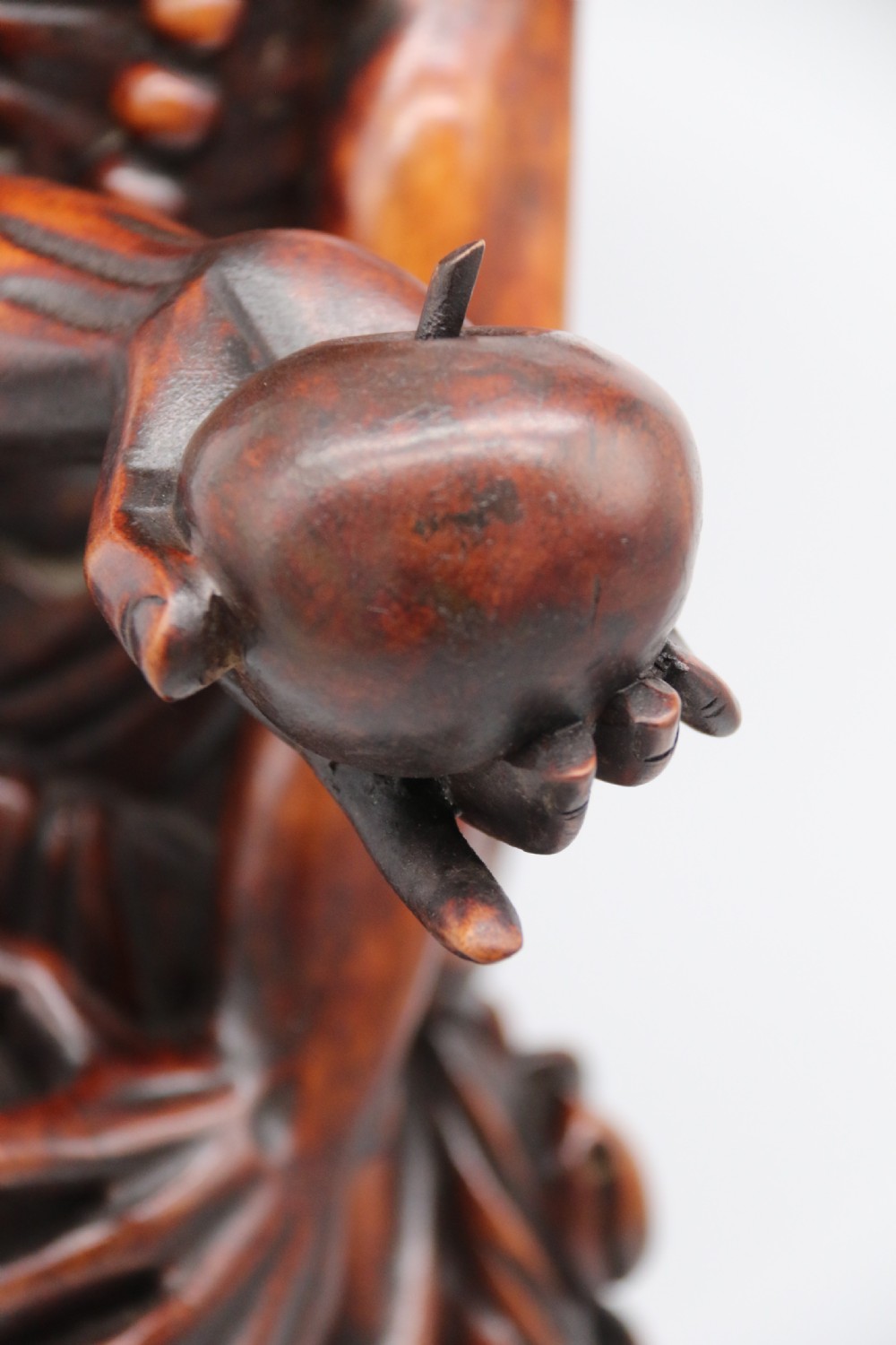 A late 19th-century Japanese Meiji period carved hardwood okimono depicting a standing male figure with a staff, scroll, and fruit on a textured base. View XII