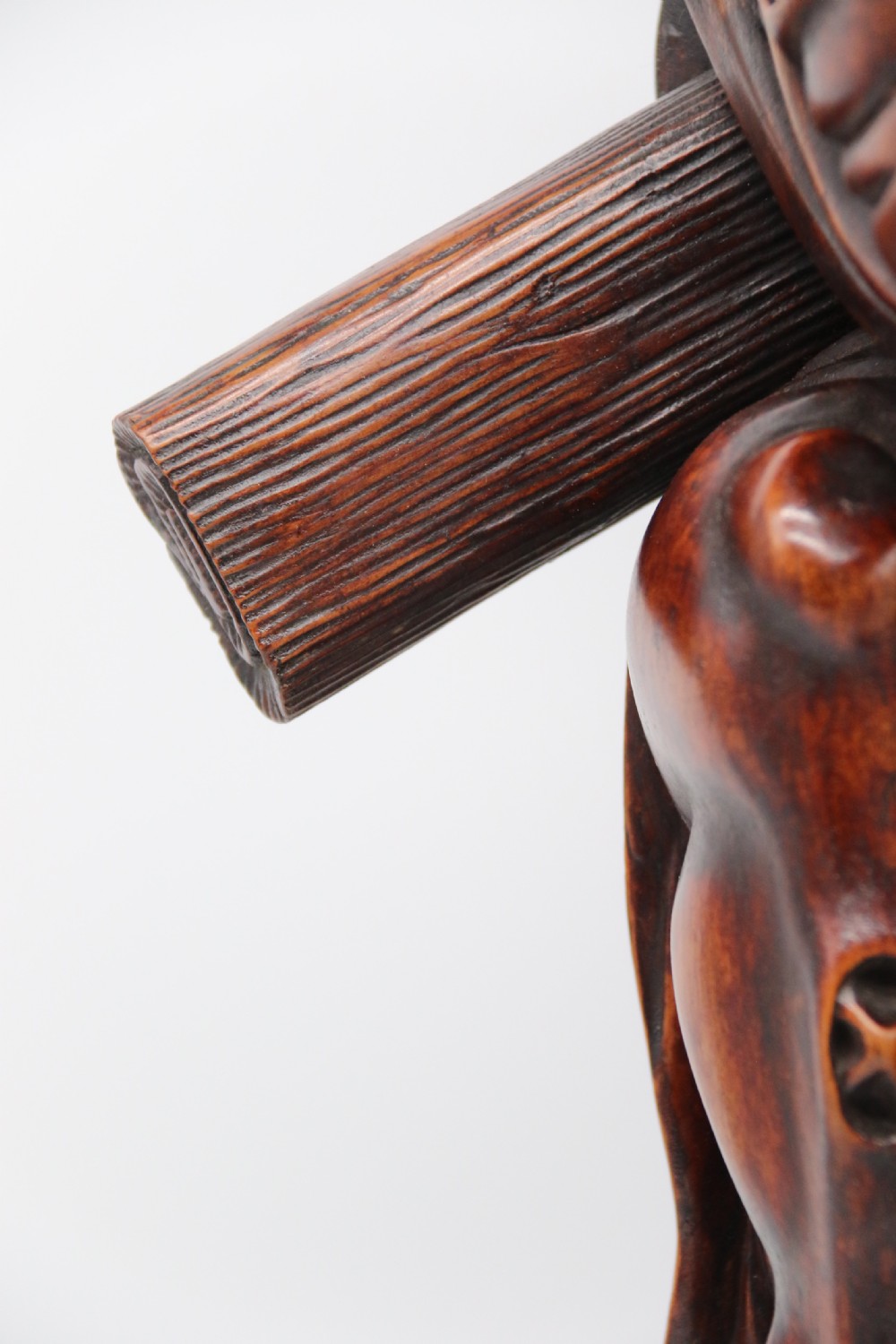 A late 19th-century Japanese Meiji period carved hardwood okimono depicting a standing male figure with a staff, scroll, and fruit on a textured base. View XV