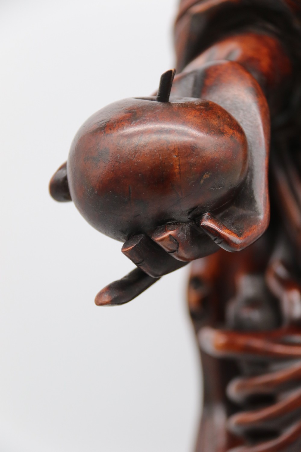 A late 19th-century Japanese Meiji period carved hardwood okimono depicting a standing male figure with a staff, scroll, and fruit on a textured base. View XVI