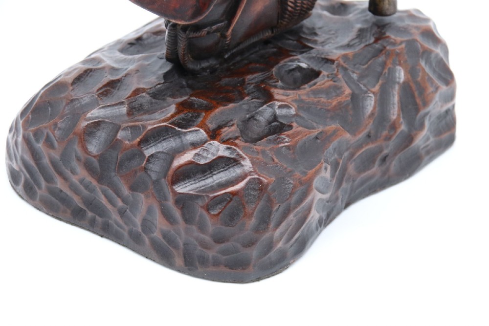 A late 19th-century Japanese Meiji period carved hardwood okimono depicting a standing male figure with a staff, scroll, and fruit on a textured base. View XXII
