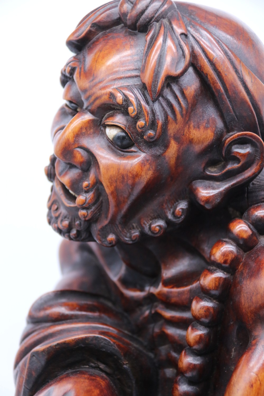 A late 19th-century Japanese Meiji period carved hardwood okimono depicting a standing male figure with a staff, scroll, and fruit on a textured base. View XXVI