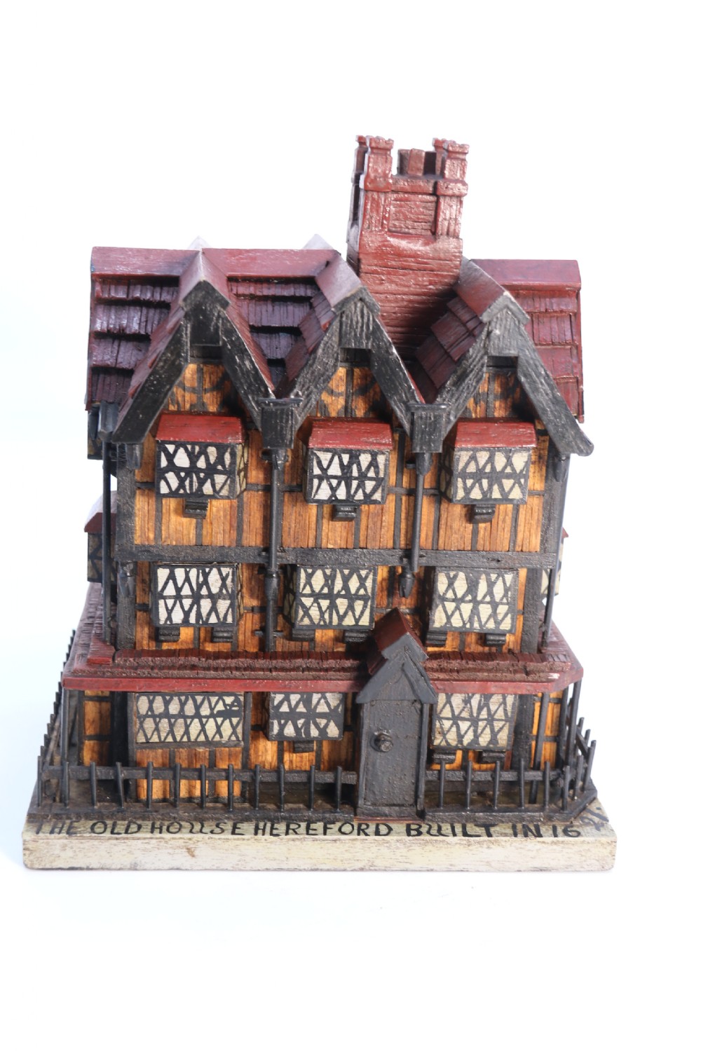 A hand-crafted matchstick model of a three-storey Tudor style half-timbered house featuring red gabled roof tiles, black timber details, and leaded window patterns on a rectangular wooden base. View II