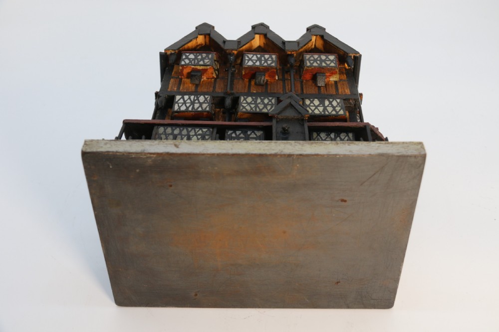 A hand-crafted matchstick model of a three-storey Tudor style half-timbered house featuring red gabled roof tiles, black timber details, and leaded window patterns on a rectangular wooden base. View XV