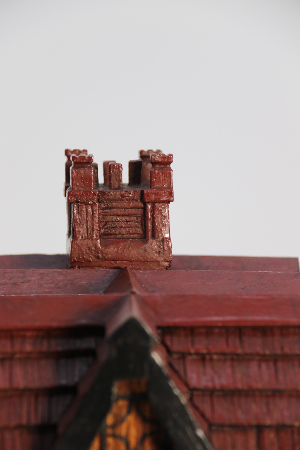 A hand-crafted matchstick model of a three-storey Tudor style half-timbered house featuring red gabled roof tiles, black timber details, and leaded window patterns on a rectangular wooden base. View XVI