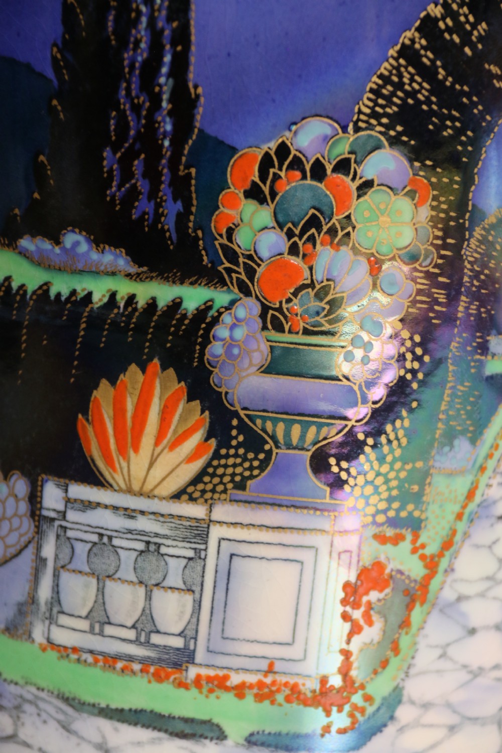 A cobalt blue ceramic lidded vase featuring a painted architectural garden scene with stone arches and gold accents. View XII