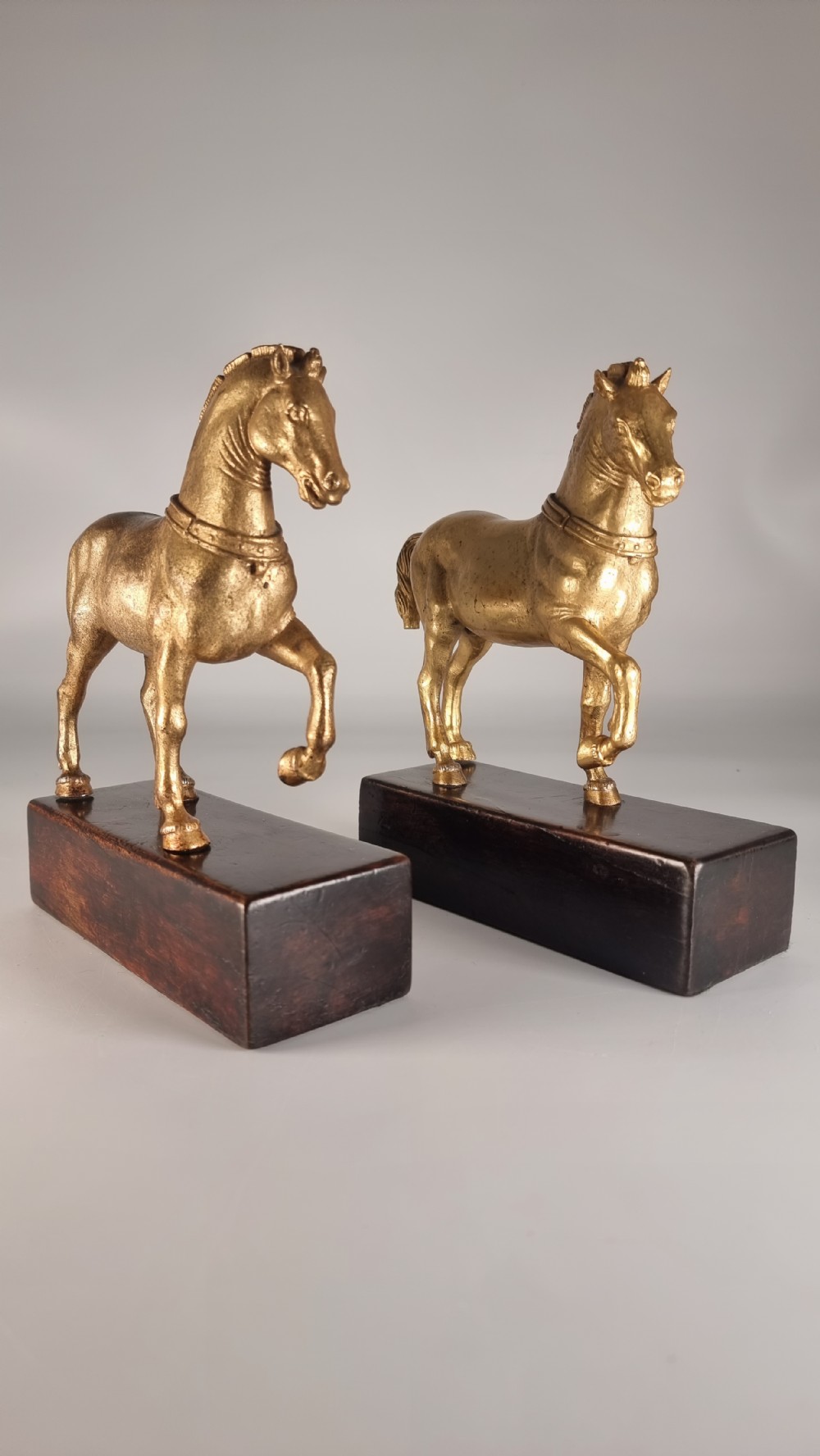 A pair of 19th-century Italian gilt bronze horse sculptures depicted facing each other, mounted on rectangular dark olive wood bases. View V