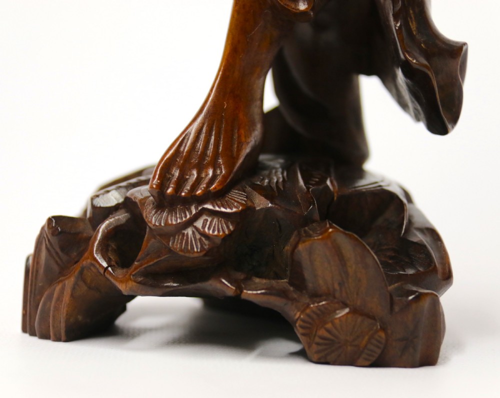 A 19th-century carved dark hardwood figure of a laughing Chinese fisherman holding a fish and a basket trap while standing on a sculpted rock base. View XI