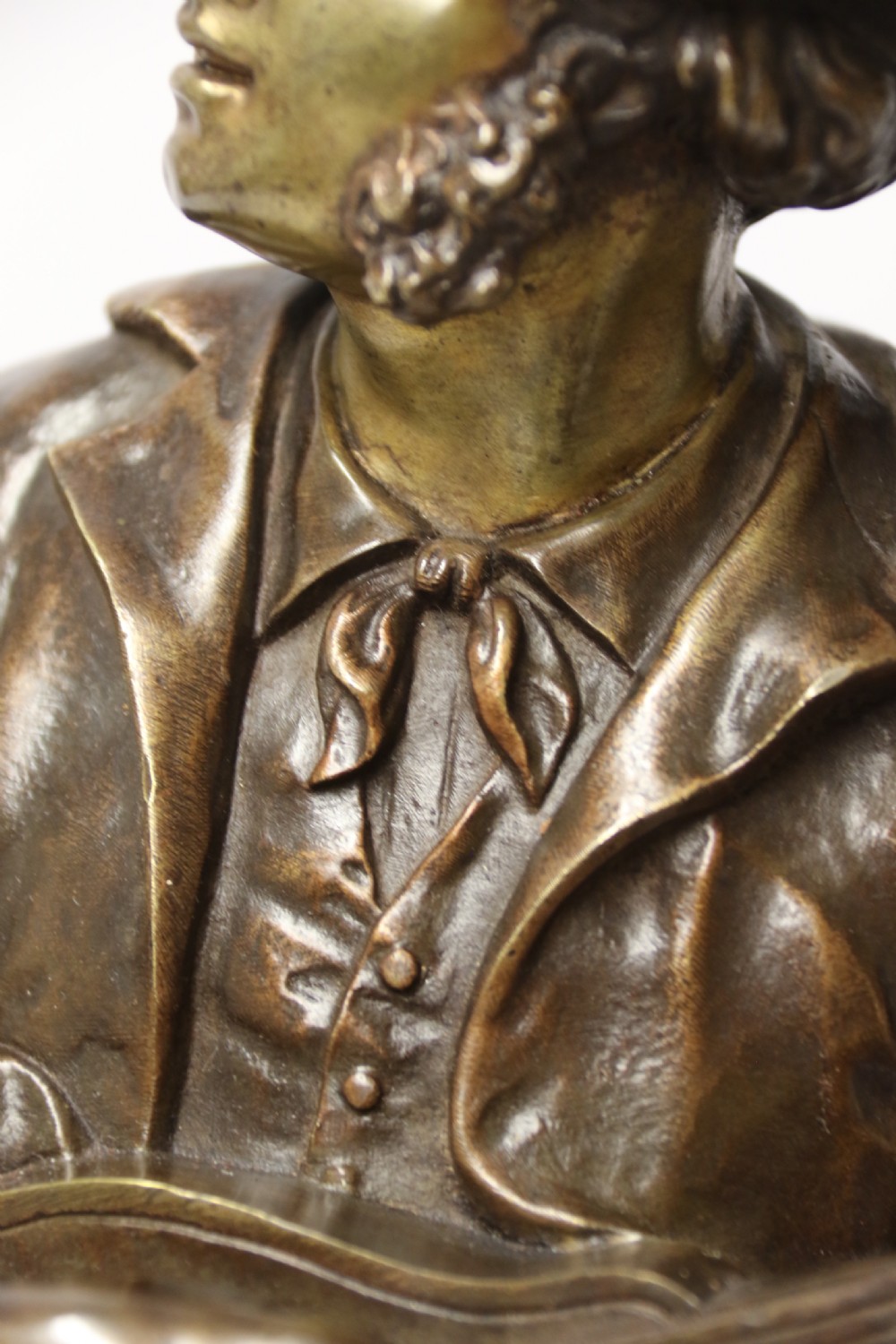 A patinated dark brown bronze sculpture depicting a standing male musician playing a mandolin while wearing a draped coat and headwear. View XIII