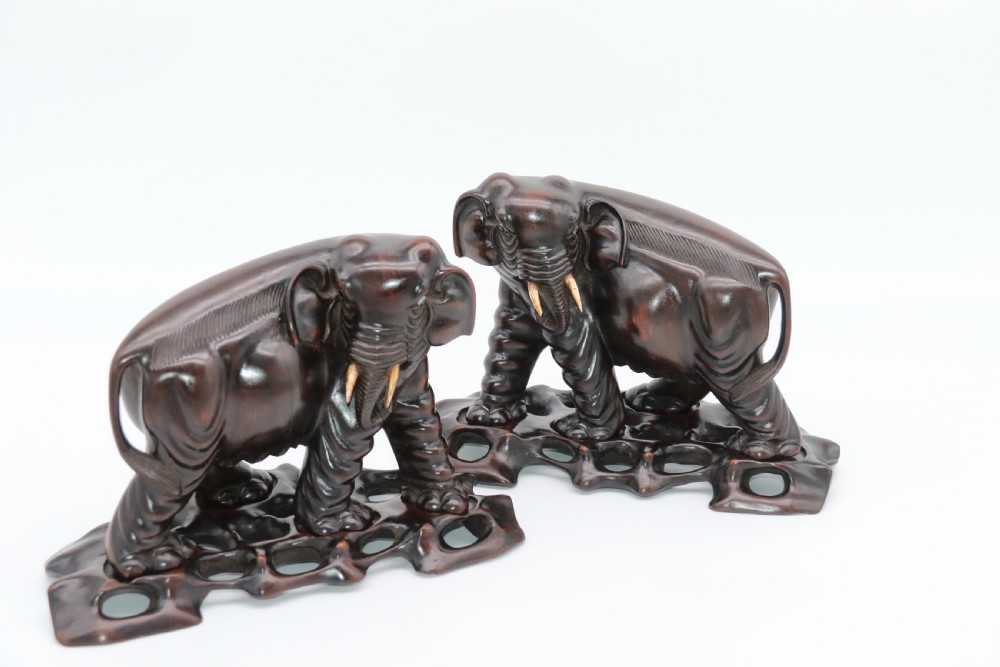 A pair of hand-carved dark hardwood elephant figures standing on pierced wooden bases with exposed tusks. View IV