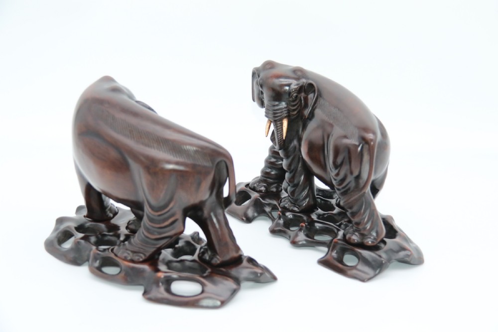 A pair of hand-carved dark hardwood elephant figures standing on pierced wooden bases with exposed tusks. View VI