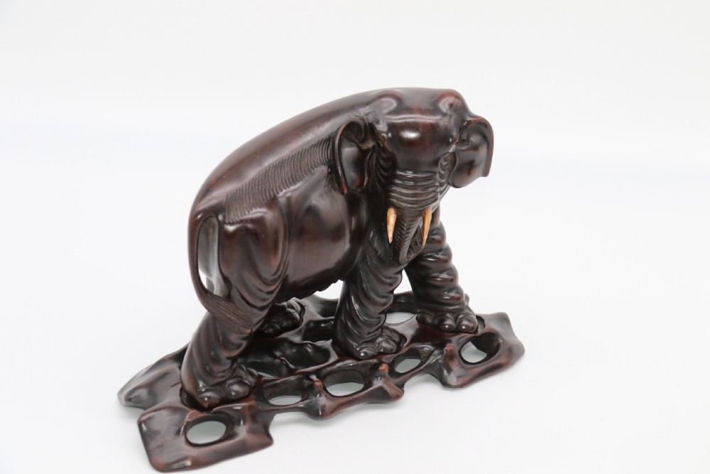 A pair of hand-carved dark hardwood elephant figures standing on pierced wooden bases with exposed tusks. View VII