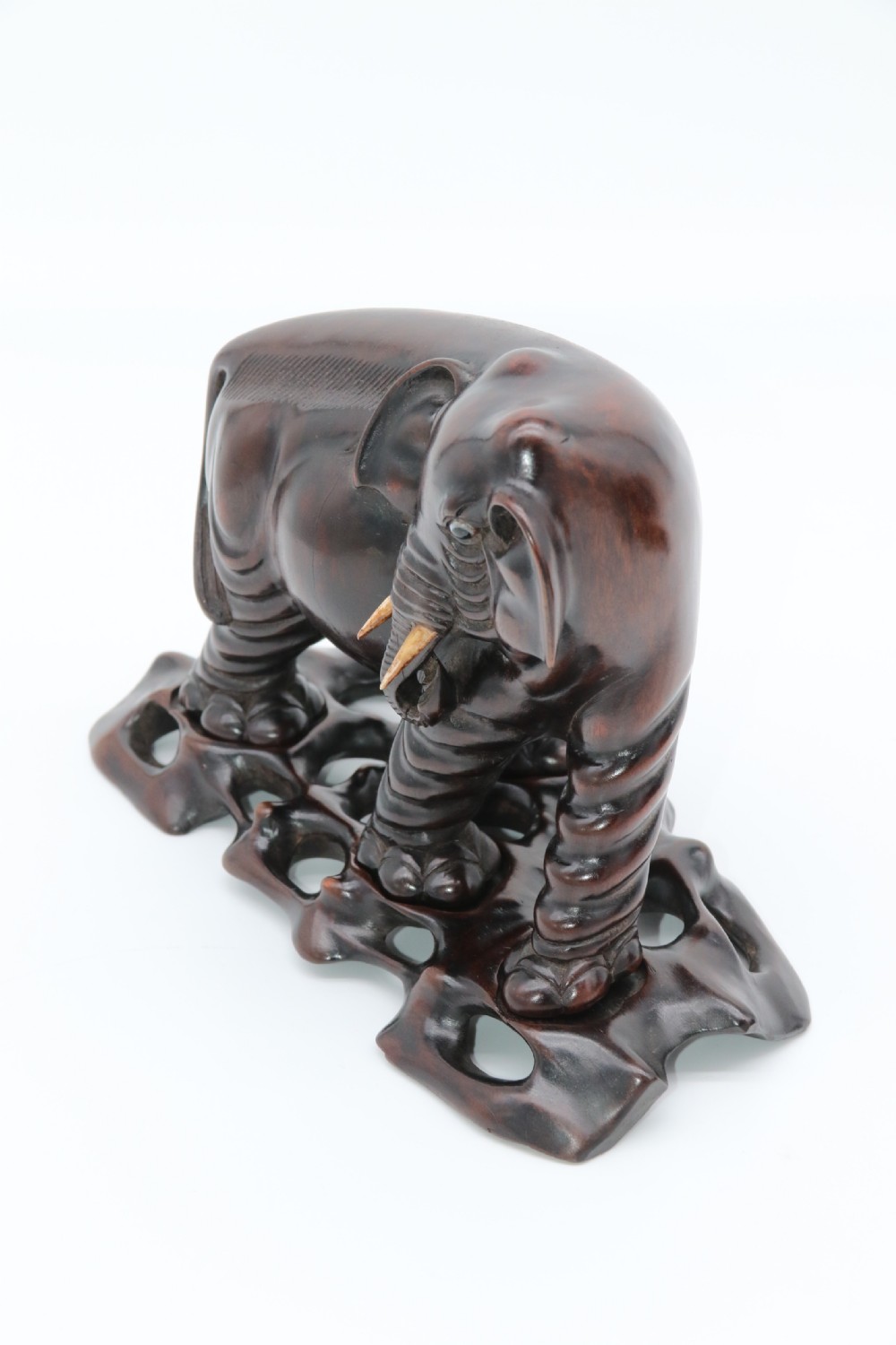 A pair of hand-carved dark hardwood elephant figures standing on pierced wooden bases with exposed tusks. View VIII