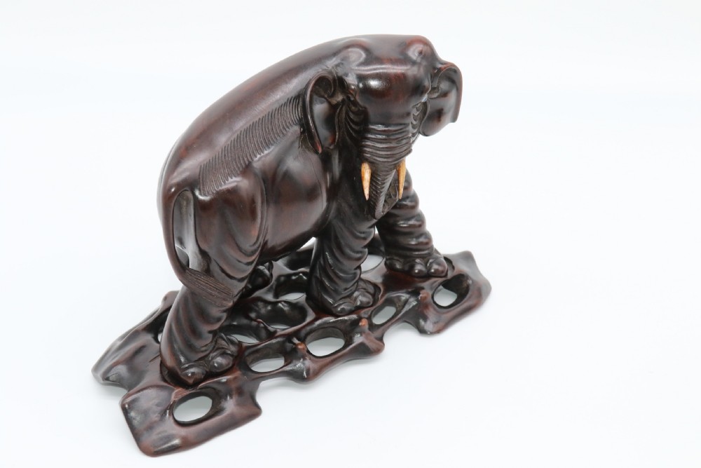 A pair of hand-carved dark hardwood elephant figures standing on pierced wooden bases with exposed tusks. View XI