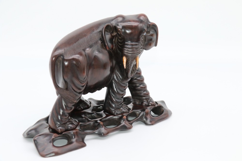 A pair of hand-carved dark hardwood elephant figures standing on pierced wooden bases with exposed tusks. View XII