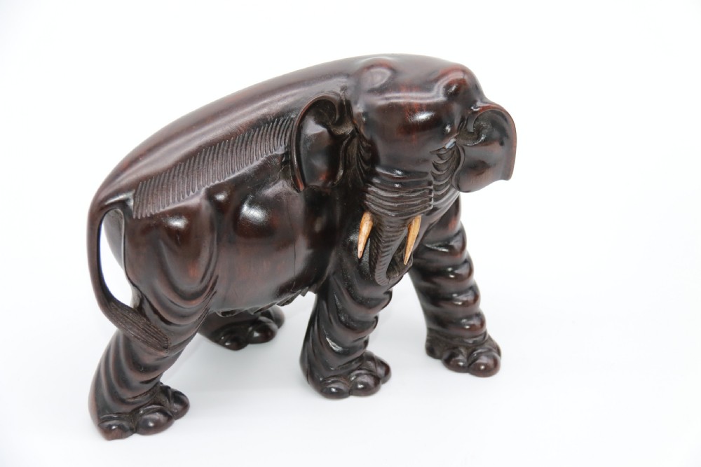 A pair of hand-carved dark hardwood elephant figures standing on pierced wooden bases with exposed tusks. View XVIII