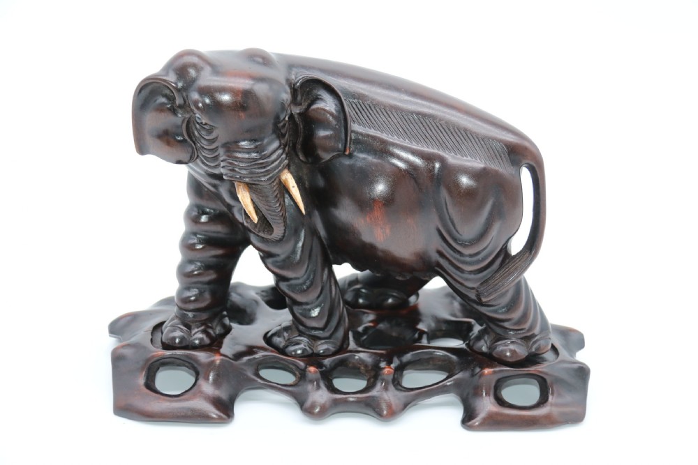 A pair of hand-carved dark hardwood elephant figures standing on pierced wooden bases with exposed tusks. View XIX
