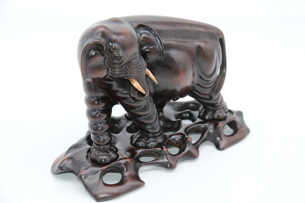 A pair of hand-carved dark hardwood elephant figures standing on pierced wooden bases with exposed tusks. View XX