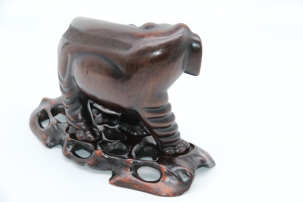 A pair of hand-carved dark hardwood elephant figures standing on pierced wooden bases with exposed tusks. View XXI