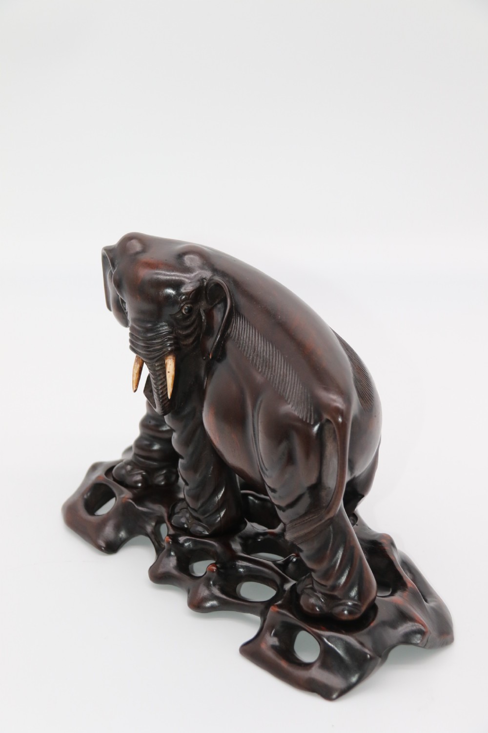 A pair of hand-carved dark hardwood elephant figures standing on pierced wooden bases with exposed tusks. View XXII